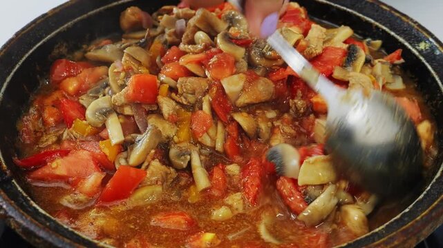 Vegetables and meat are simmering in a deep cast-iron skillet
