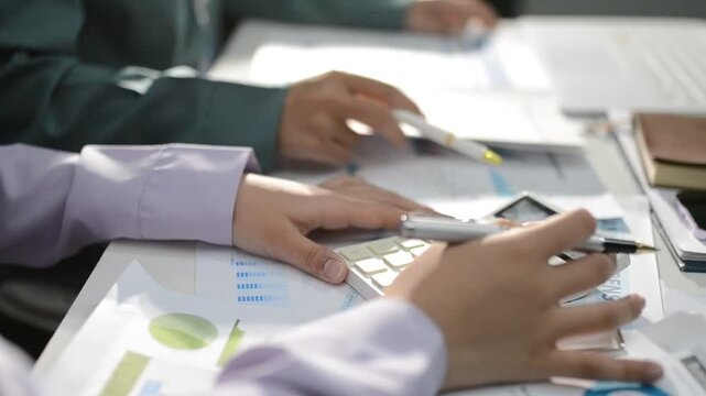Close up of two asian colleagues working together, have a disussion and using laptop computer at office with financial document on desk