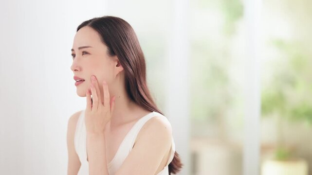 鏡を見て肌を気にする日本人女性