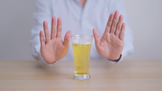 man making stop hand gesture to refuse a glass of Beer, Healthy man say no to alcohol drink, stop alcoholism and addiction concept. Responsible man reject a drink before driving and quit booze