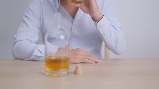 Stressed man drinking whiskey alone with problem. Exhausted drunk man looking stressed and sleepy. Alcohol addiction, Alcoholism, emotional distress and mental health concept
