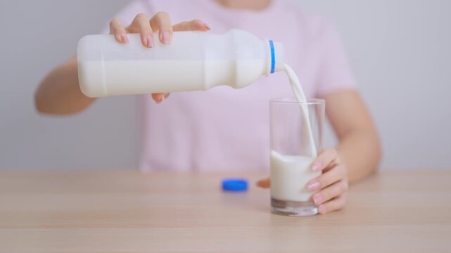 Healthy woman pouring fresh milk into glass at home, female drinking for calcium and strong bones, high protein, dairy product for healthy lifestyle, wellness and daily routine concept