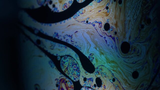 Gasoline fluid. Ink blend. Defocused orange blue color drop round texture chemical liquid floating on abstract dark black background.