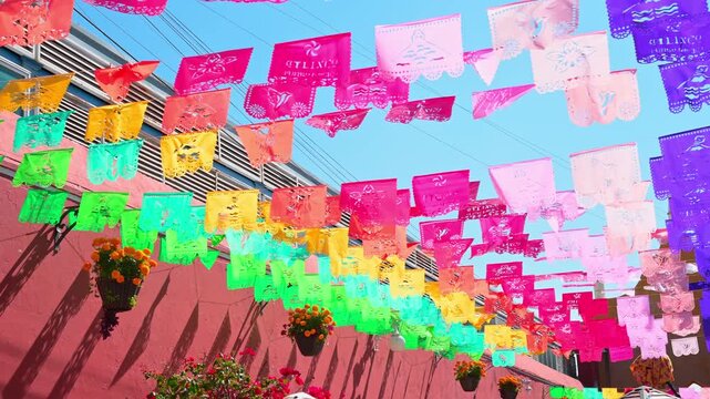 Colorful Mexican papel picado paper banners hanging outdoors during a traditional festival or street celebration