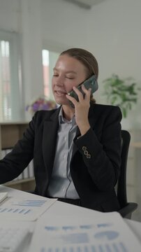 Businesswoman talking on smartphone while working with documents