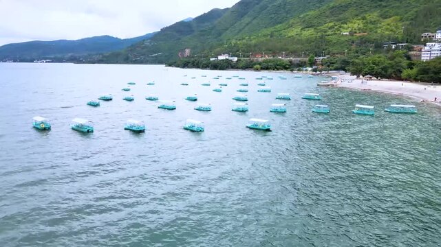 Blue pedal boats floating on Dianchi Lake near Kunming with green hills and shoreline in background