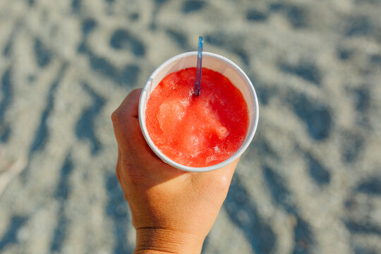 Strawberry granita held over sandy beach
