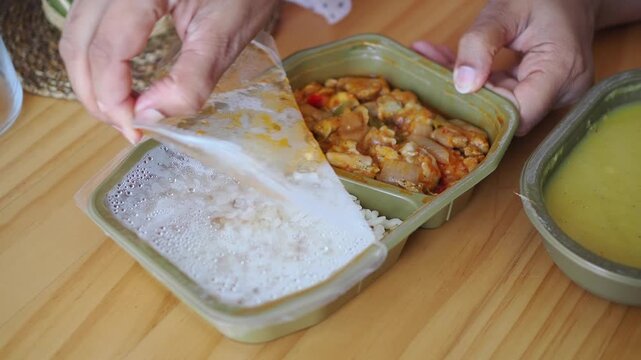 Person Opening Plastic Film Lid on Prepackaged Meal Container