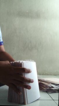 Hands Sorting Stack of White Paper Documents on Tiled Floor