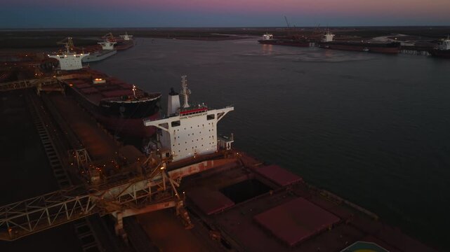 Aerial of raw materials being loaded onto a ship in Port Hedland Australia at sunset