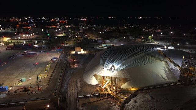Excavators load raw material onto conveyors for shipping port hedland australia at night
