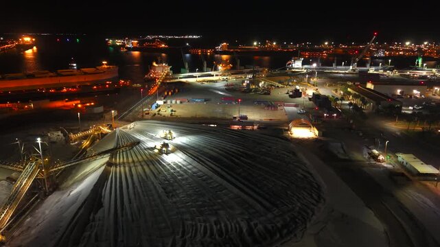 Excavators load raw material onto conveyors for shipping port hedland australia through the night