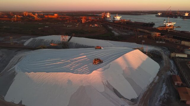 Excavators load raw material onto conveyors for shipping port hedland australia at golden hour sunset
