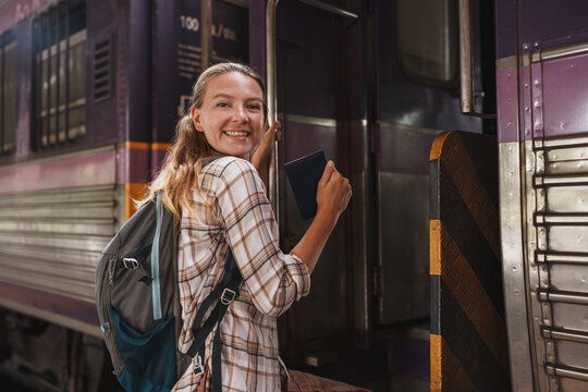 Woman backpacker boarding train holding passport