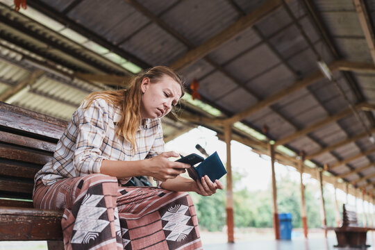 Woman experiencing travel problems at train station checking documents