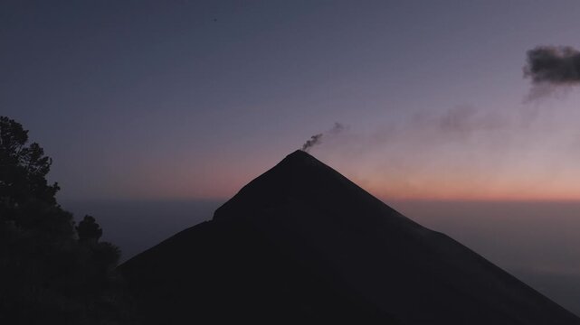 Volcan de Fuego eruption captured by drone at sunrise, colorful dawn sky and ash cloud above volcano