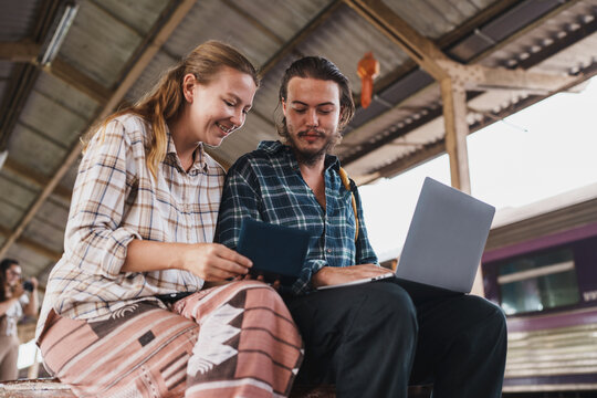 Couple planning travel using laptop at train station