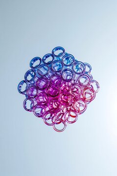 A circular cluster of many small glass test tubes with a blue to pink gradient color effect arranged in a honeycomb pattern against a light background
