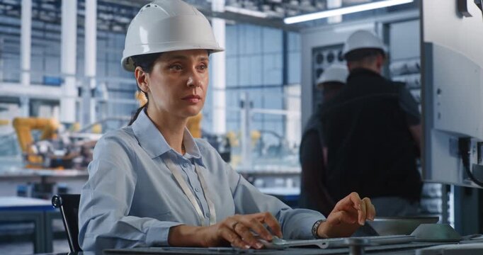 Professional Female Engineer Inspects Assembly of Automotive Frames at Workstation at High Tech Facility. Smart Industrial Automation and Server Maintenance Enhance Modern Automotive Manufacturing.