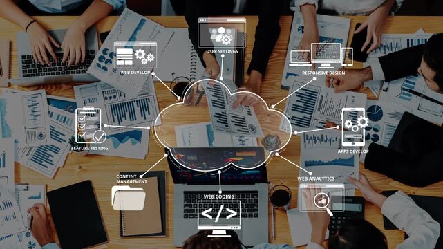 A top-down view of a collaborative workspace featuring hands working with digital tools, charts, and data analysis for web and app development in a modern office setting. Raster