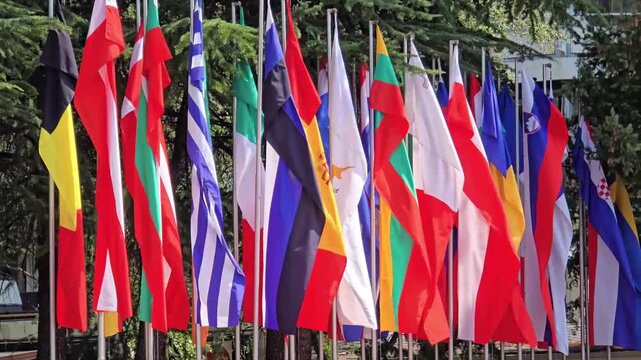 National flags on poles with trees on the background.
