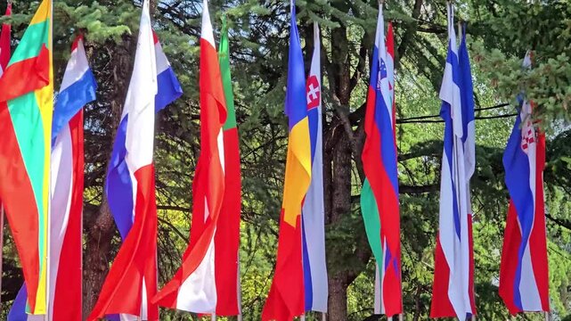 National flags on poles with trees on the background.