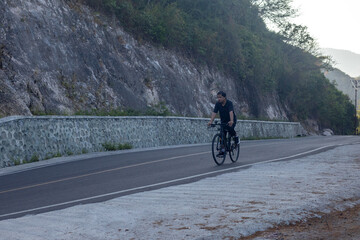 Fototapeta premium Cyclist Riding on a Mountain Road
