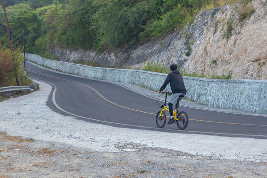 Cyclist Riding Folding Bicycle on Mountain Road
