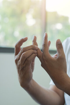 Sihouette-style shot of a person examing and rubbing their fingers and palms