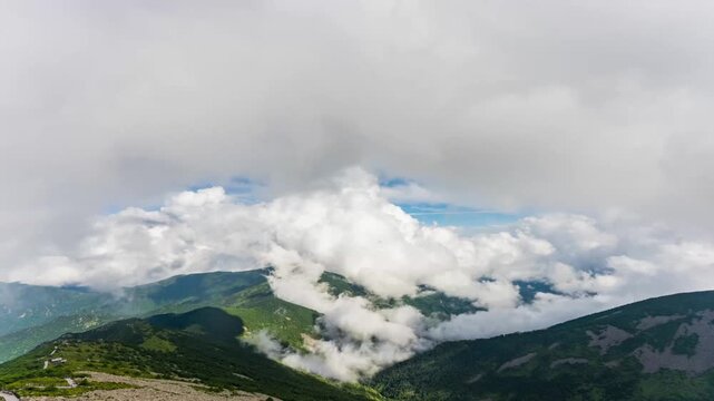 Majestic cloud sea rolling over Qinling Taibai Mountain ridges under bright blue sky, time-lapse aerial view