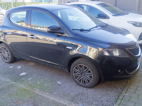 Black Lancia Ypsilon hatchback parked on urban street, offering compact Italian design and practical city transport, showcasing contemporary automotive style and everyday mobility
