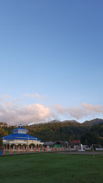 Beautiful mosque with a blue roof set against lush mountains under a clear sky