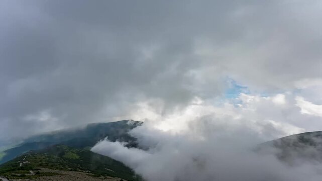 Time-lapse of rolling cloud sea enveloping Qinling Mountains peaks with patches of blue sky and green forested slopes