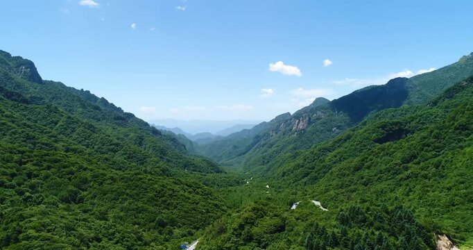 Aerial drone view of lush green mountain valley with winding road through Qinling Mountains south of the watershed