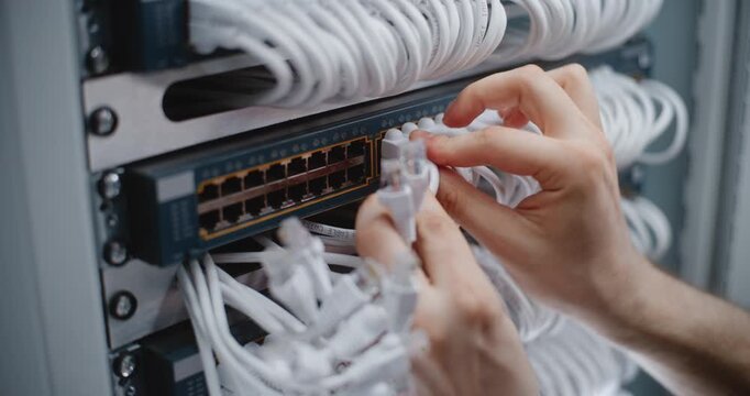 Close Up of Hand Male Specialist Performs Rack Cabling Maintenance, Connecting Patch Cords and Arranging Cable Bundles Between Patch Panel, Switch For Clean Infrastructure and Stable LAN Connectivity.
