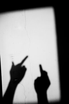 Close up shadow of two hand showing middle finger gesture on the dirty wall