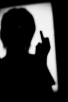 Close up black and white shadow of portrait a man with middle finger hand gesture on the dirty wall