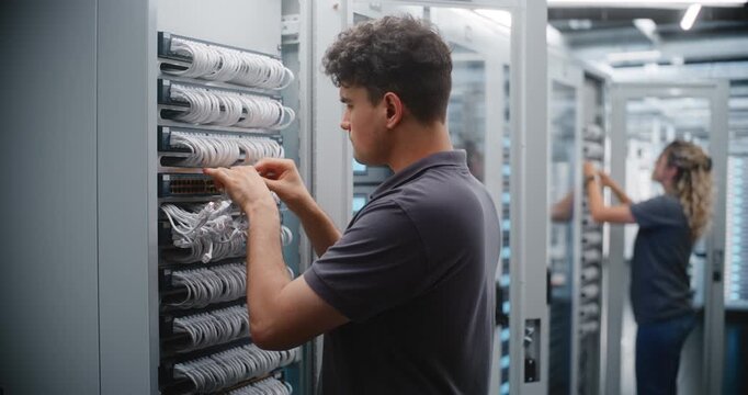 Male IT Technician Services Server Rack Cabling While Female Colleague Maintains Nearby Equipment, Demonstrating Structured Cabling Teamwork, Physical Layer Maintenance and Coordinated Operations.