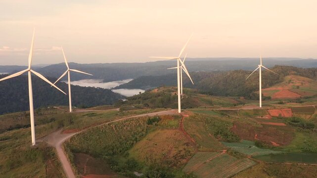 Aerial view of powerful Wind turbine farm for energy production on beautiful cloudy sky at highland. Wind power turbines generating clean renewable energy for sustainable development green energy.