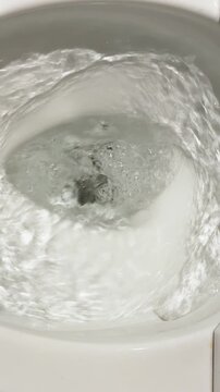 Close Up of Water Swirling and Flushing in White Ceramic Toilet