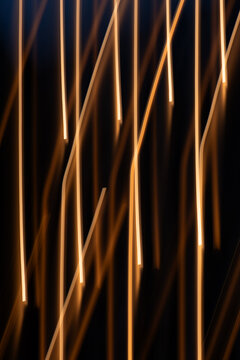 Vertical low-key photograph of abstract warm golden light streaks created with intentional camera movement (ICM). For fiber optic data transmission, high-speed internet, digital connectivity, network 