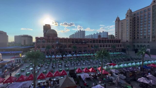 Urumqi Starlight Night Market food street bustling with vendors and diners under golden hour sun, Xinjiang China