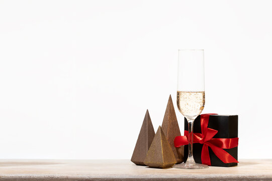 Minimalist holiday background  with black gift box and sparkling champagne glass  a present box with red bowl for sophisticated winter sales and e-commerce ads.