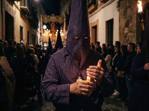 Penitent in purple capirote holding a candle during Semana Santa procession