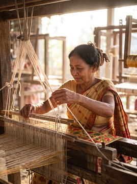 Assamese woman weaving traditional silk fabric on a wooden handloom in Sualkuchi