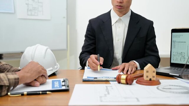 Professional lawyer and contractor discussing a real estate construction contract, reviewing architectural blueprints and legal documents