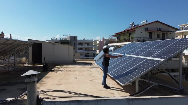 Woman inspecting solar panels on an urban rooftop in Athens, Greece