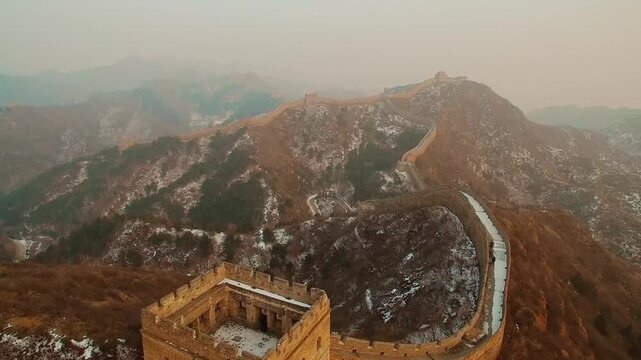 Great Wall of China at Badaling during winter sunrise, aerial drone view over snow-dusted mountains and historic watchtowers