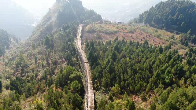 Aerial view of ancient stone wall winding through forested mountain ridge in Zhenyuan, Guizhou