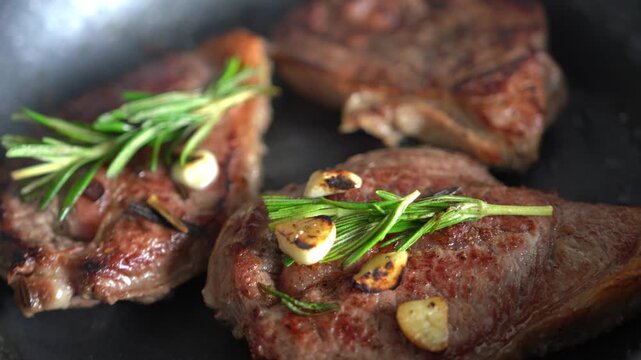 Cooked beef steak. Close-up. Beef steak in a frying pan with sprigs of rosemary.